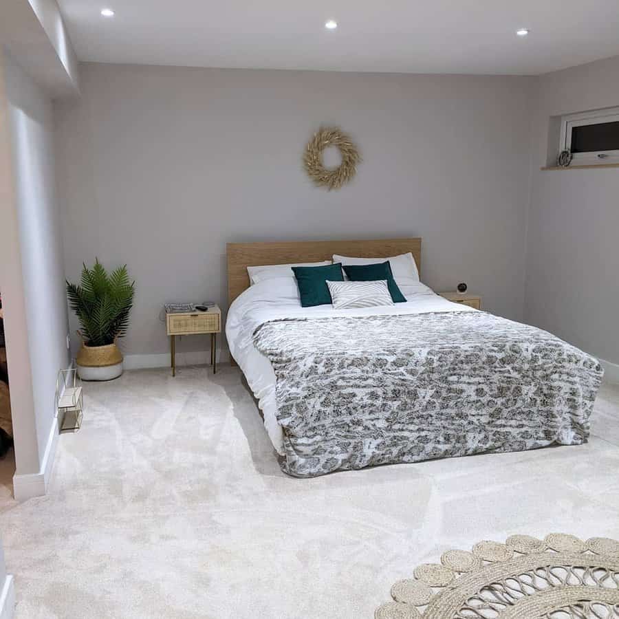 Minimalist attic bedroom with soft neutrals, a wooden bed frame, and cozy textures. Subtle greenery and warm lighting create a calming retreat.