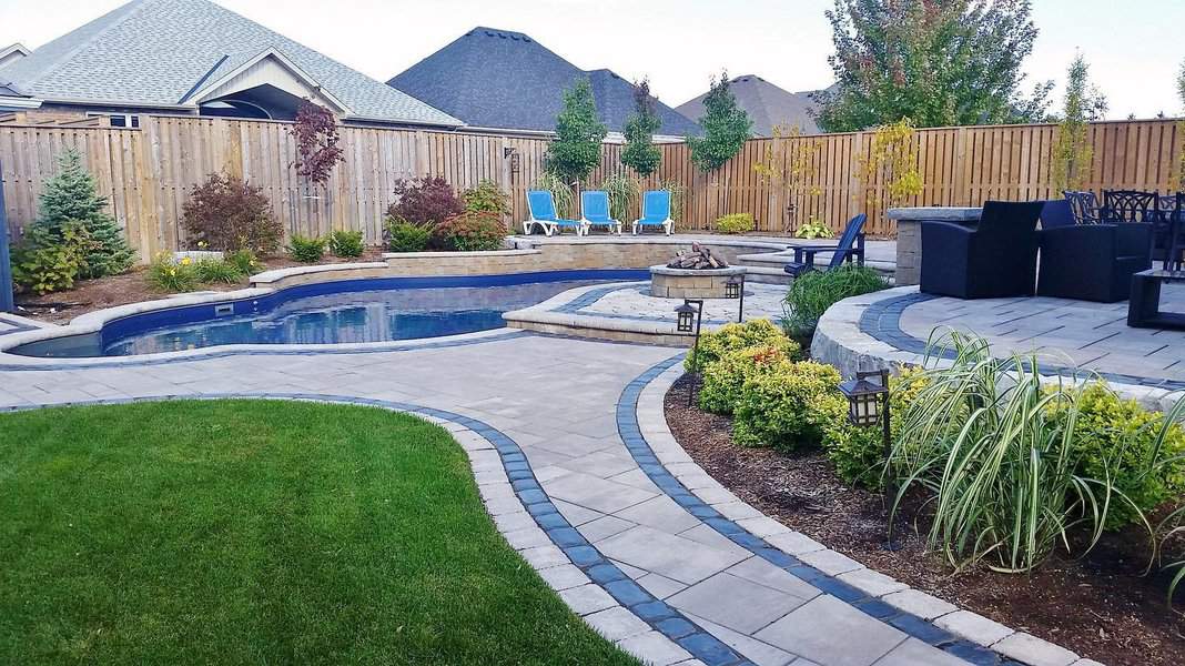 Luxurious backyard with a sleek in-ground pool, stylish paver walkway, cozy fire pit, lounge chairs, and lush landscaping for a resort feel