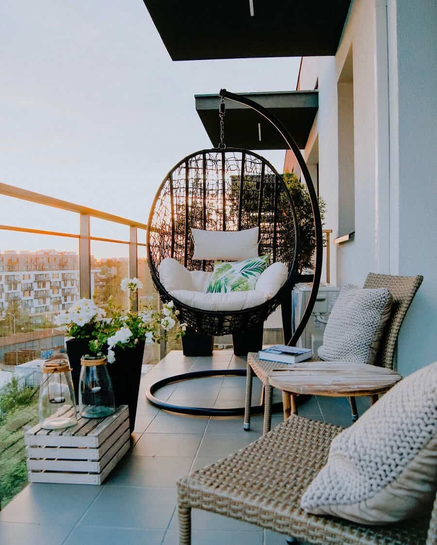 Balcony with a hanging egg chair, cushions, potted plants, a small table, and outdoor seating overlooking a scenic view