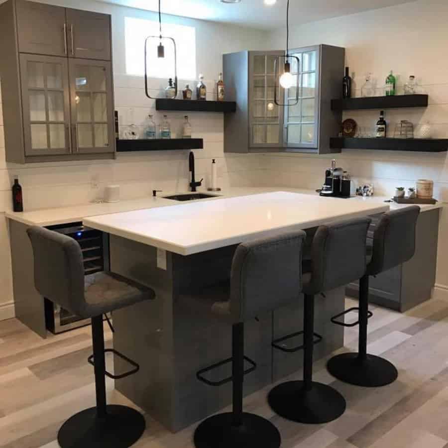 Sleek basement bar with gray cabinets and pendant lights