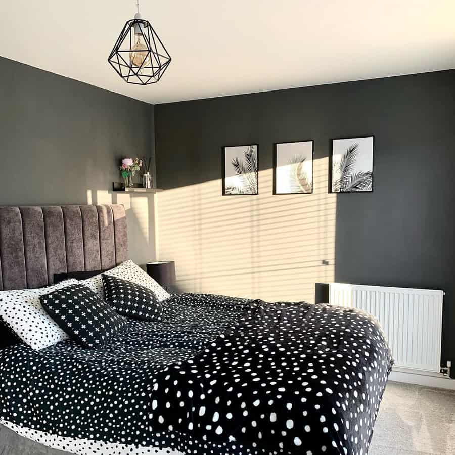 Bright black bedroom with polka dot bedding, tufted headboard, palm leaf prints, and sunlight casting playful shadows on the wall