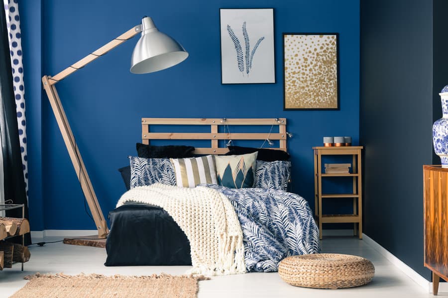 Blue bedroom with throw pillows, throw blankets, and woven mat