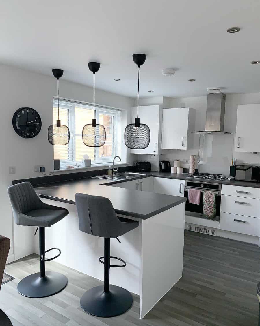 Modern monochrome kitchen with a sleek black and white breakfast bar, quilted gray barstools, mesh pendant lighting, and minimalist decor