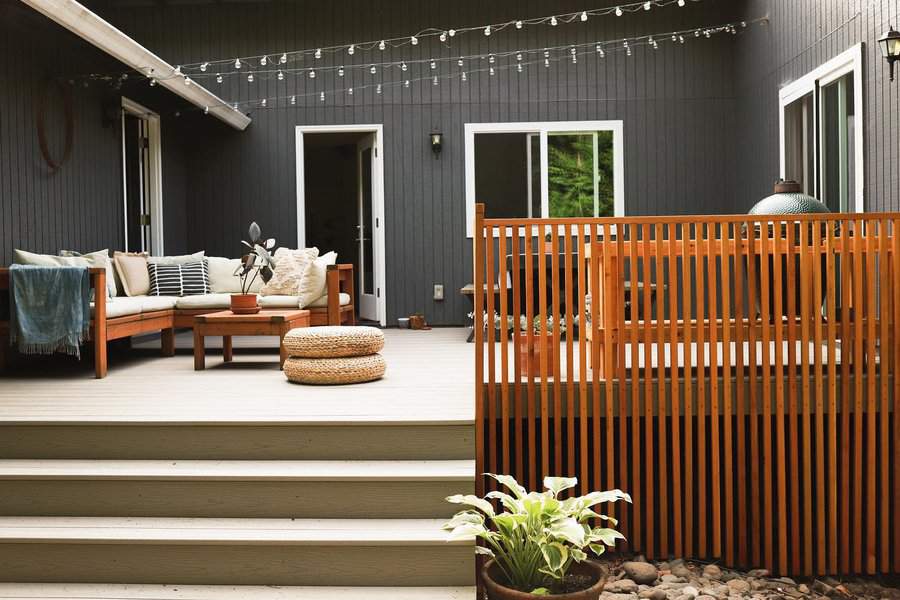 A cozy deck with wooden furniture and a slatted privacy screen