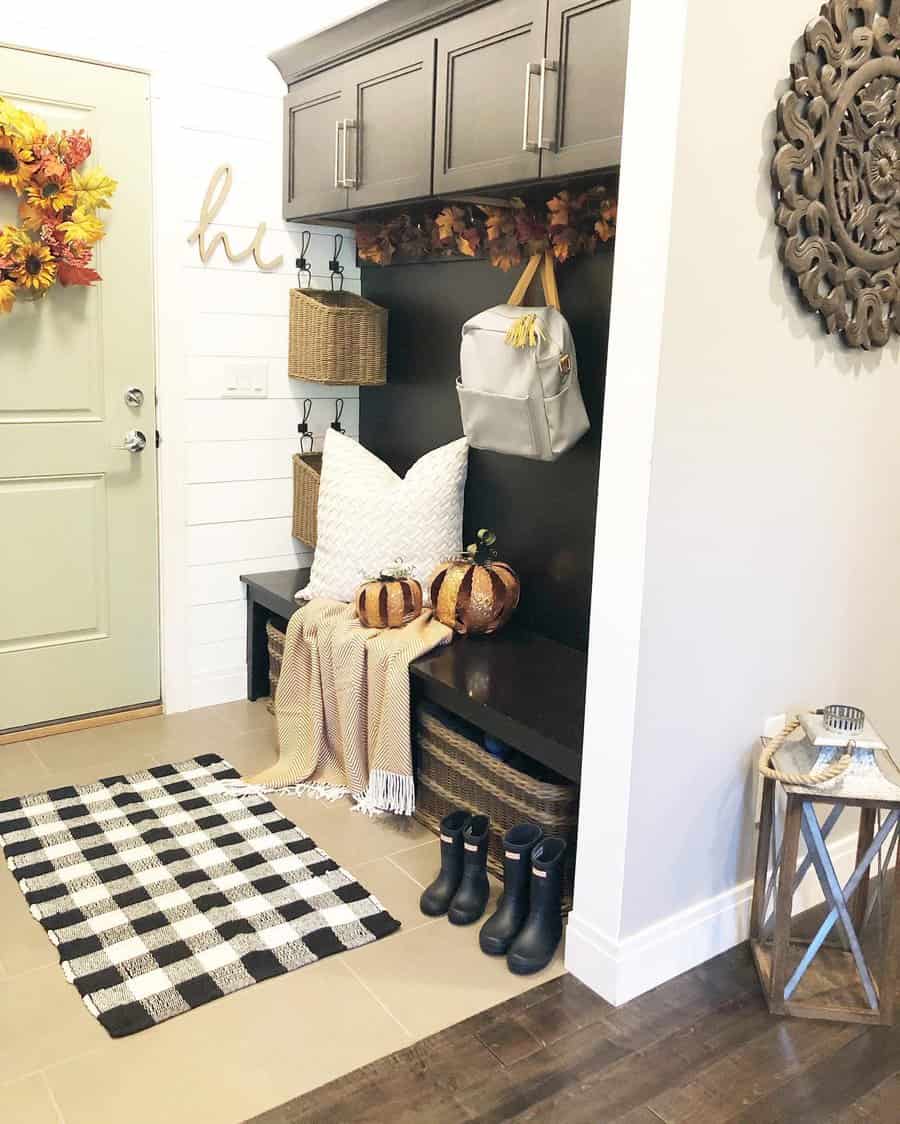 Cozy entryway with dark wood storage, woven baskets, fall decor, and a checkered rug, creating a warm and inviting seasonal touch