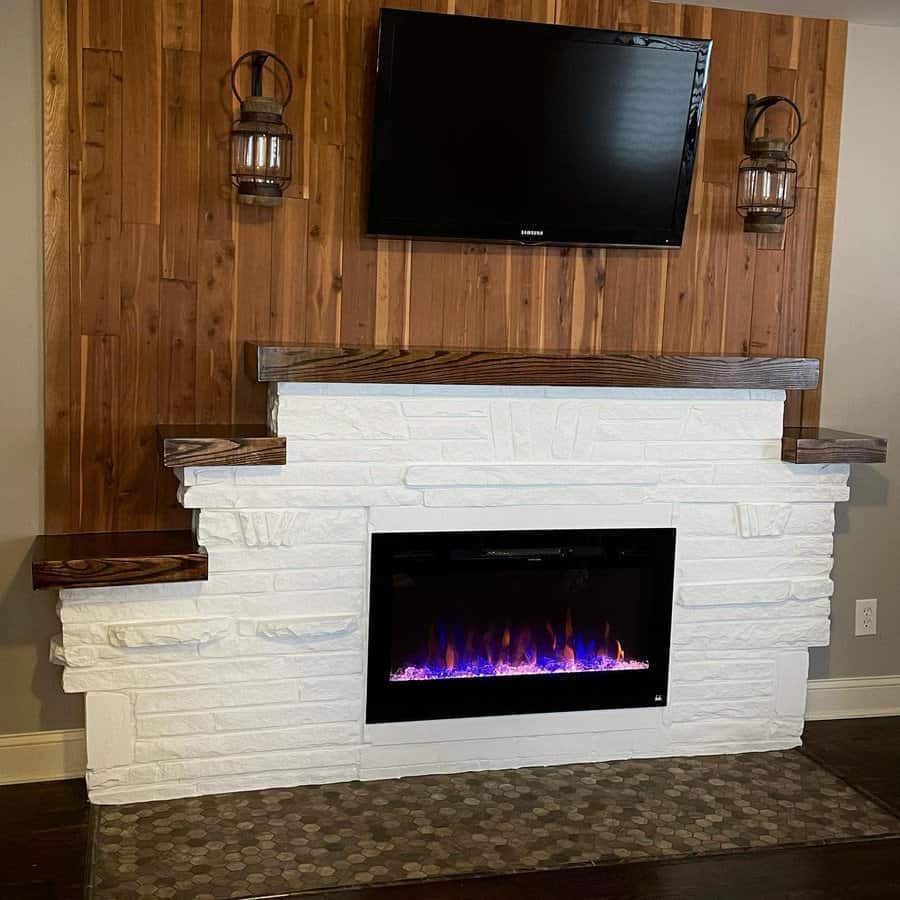 A contemporary fireplace with a white stone surround, wooden mantel, and wall-mounted TV, complemented by lantern-style lighting for a modern, rustic vibe