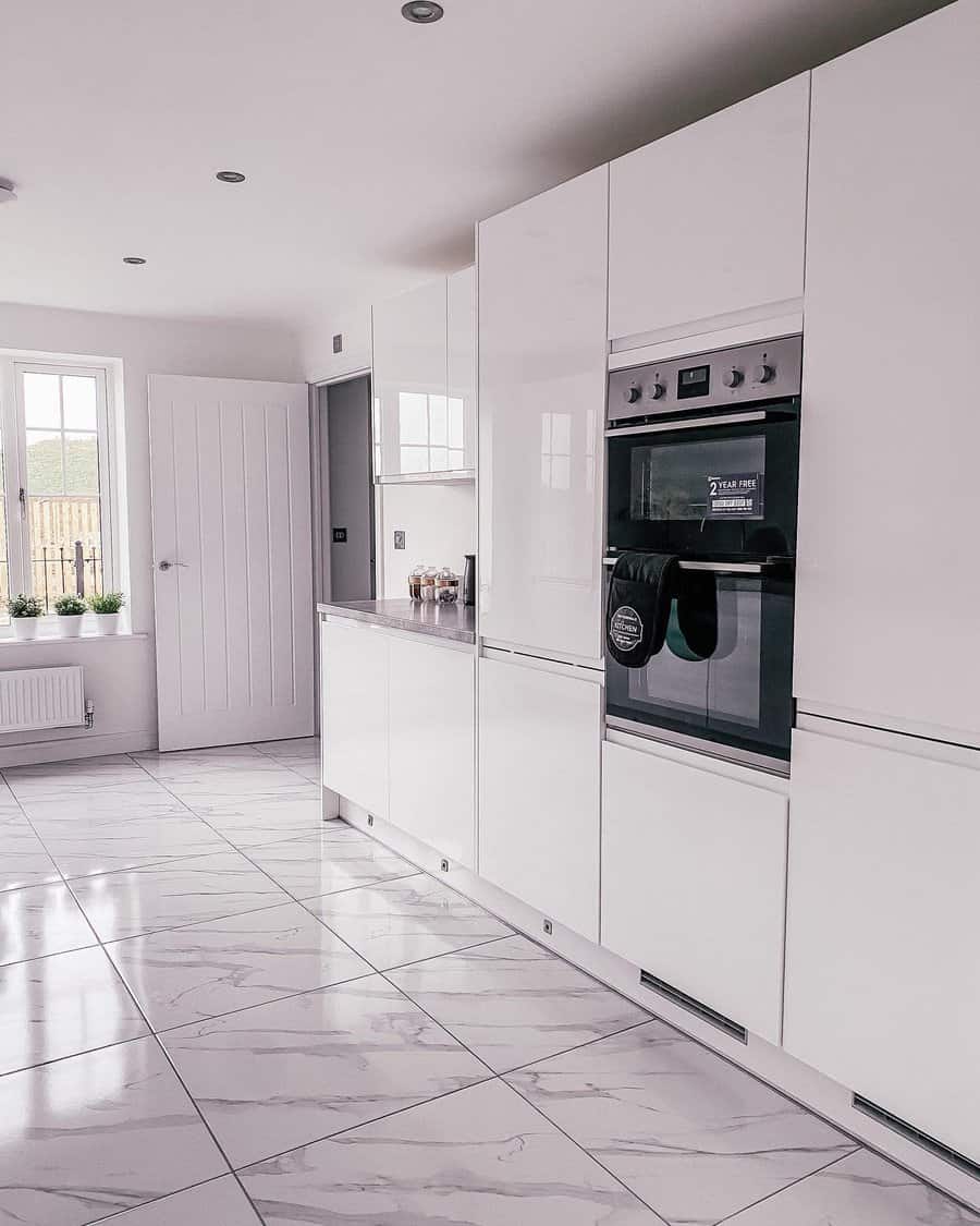 Sleek kitchen with glossy white cabinets and tiled floor