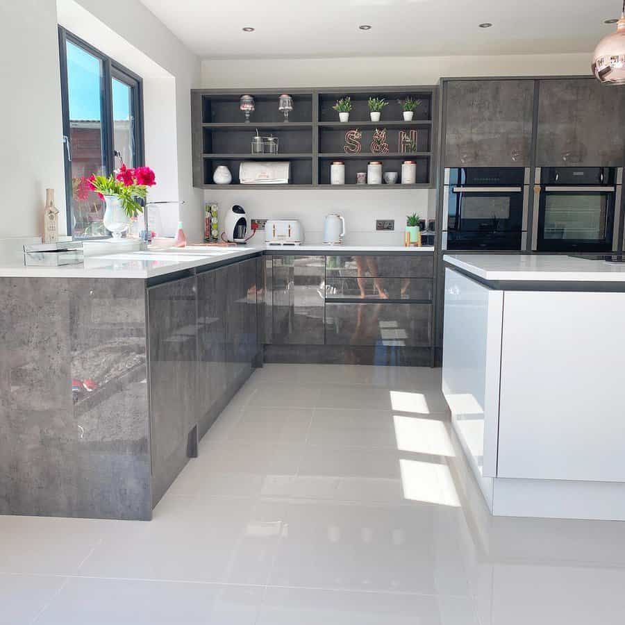 Glossy white tile flooring enhances this modern kitchen, reflecting natural light and complementing sleek grey cabinetry for a clean, sophisticated look