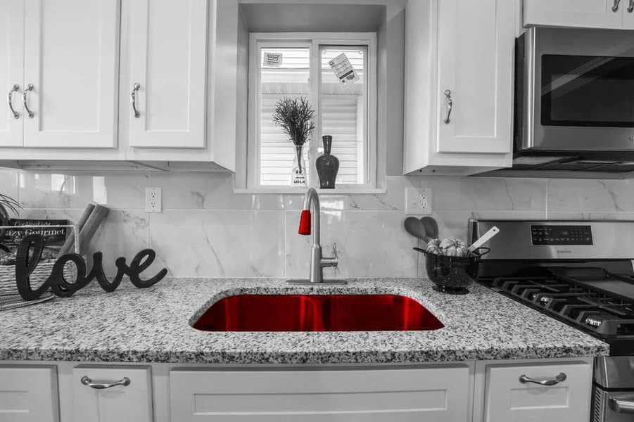 Black and white kitchen with a red-lit sink, granite countertop, and modern appliances