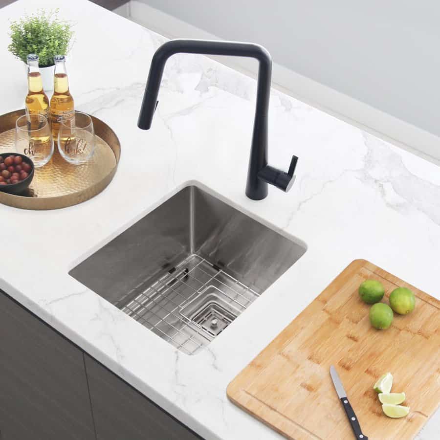 Minimalist kitchen with a sleek undermount sink, bold black faucet, marble countertop, and wooden cutting board for a modern touch