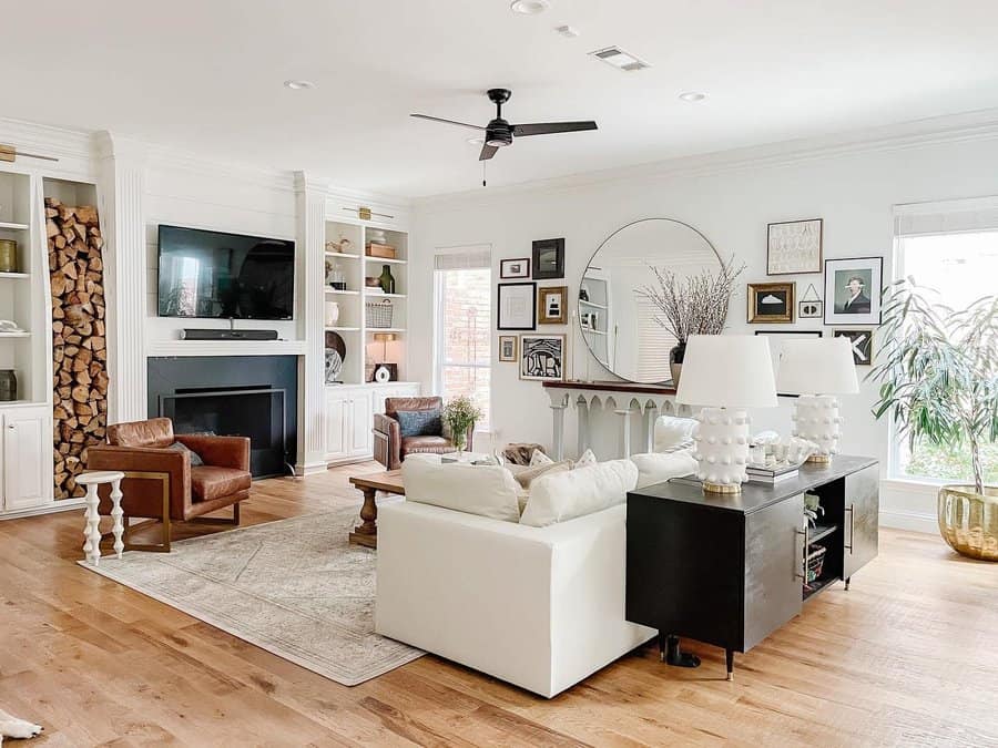 Modern living room with white sofa, fireplace, large mirror, and wooden floors