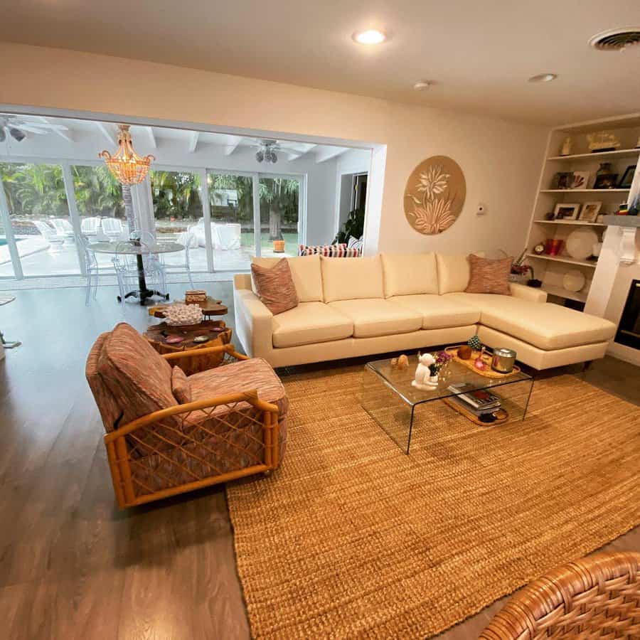 Cozy open-concept living room with a neutral sectional, rattan accents, and a seamless indoor-outdoor transition to a poolside patio