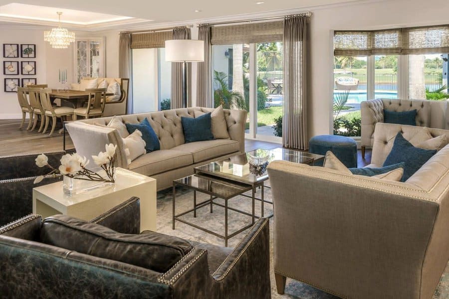 Elegant open floor plan with a luxurious living area, plush seating, blue accents, and a dining space overlooking a scenic outdoor view