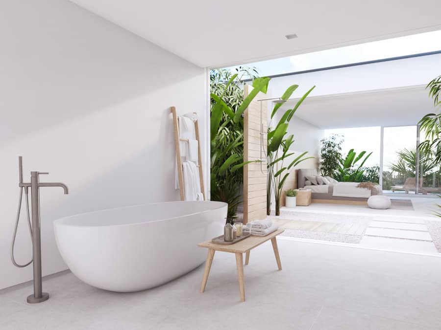 Minimalist indoor-outdoor bathroom with a sleek freestanding tub, open shower, and lush greenery for a serene spa-like retreat