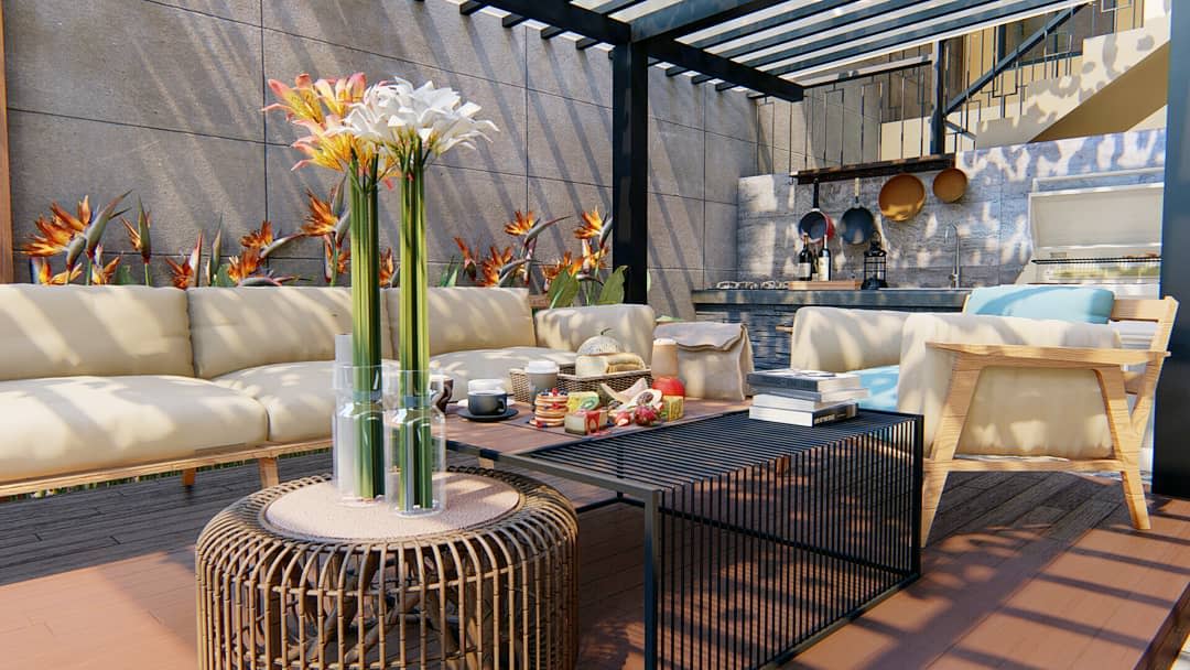 Modern outdoor patio with beige sofas, a black metal coffee table, flowers, books, and dining setup featuring a pergola and barbecue area in the background