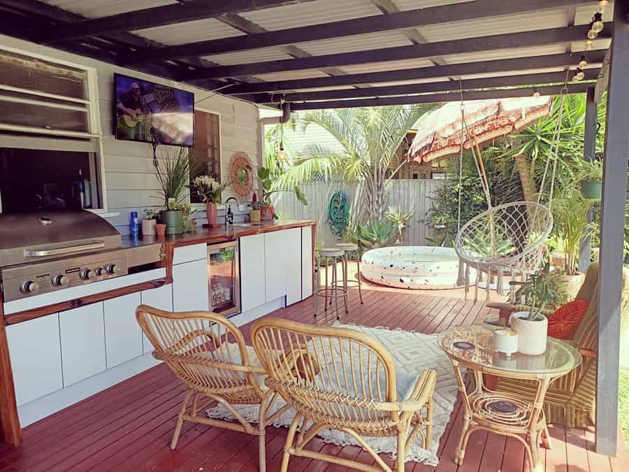 Outdoor patio with a grill, TV, seating area, hammock chair, and a small pool surrounded by lush plants and trees