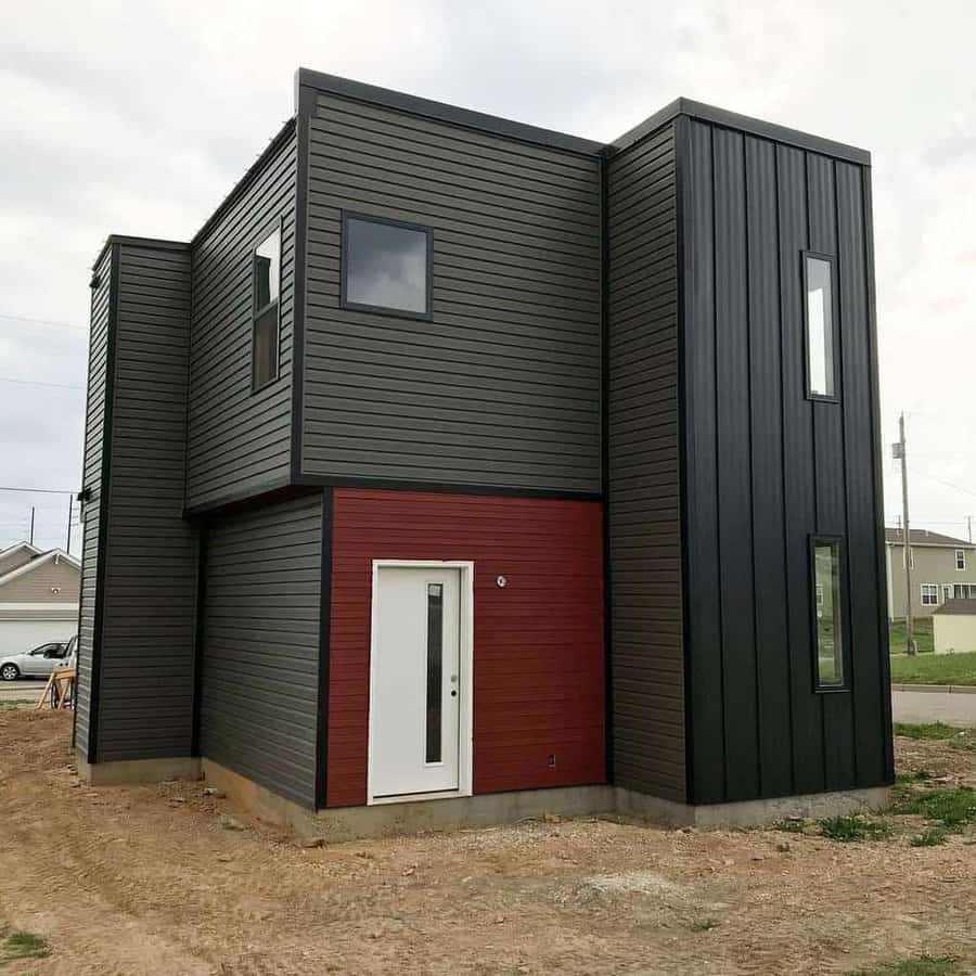 Modern two-story house with dark exterior and a white-framed door