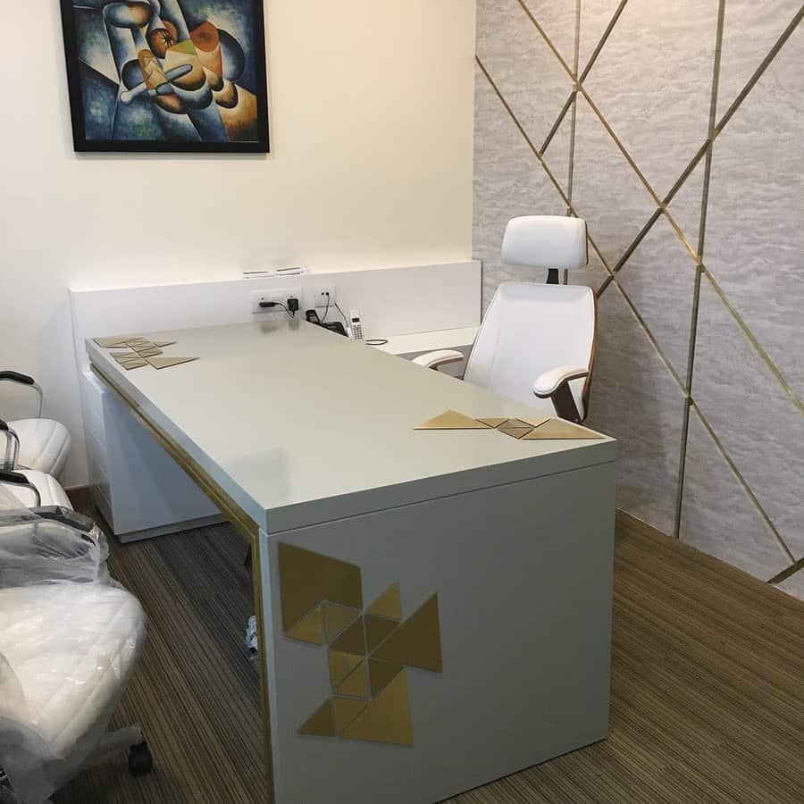 Modern office with a sleek desk, two white chairs, geometric wall art, and a light accent wall with gold lines