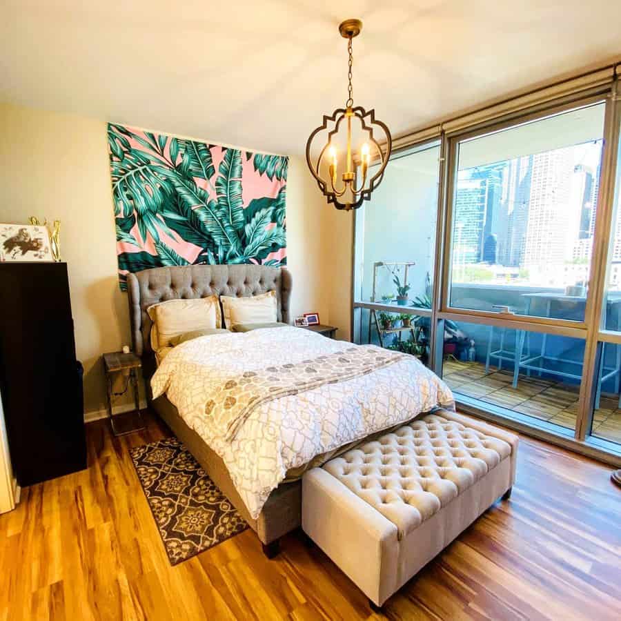 Bedroom with large window, city view, and tropical tapestry