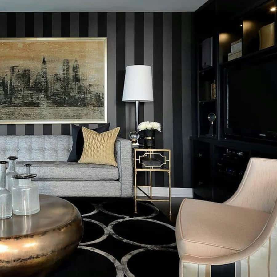 Modern living room with striped wallpaper, gray sofa, gold accents, round coffee table, and abstract cityscape artwork in neutral tones