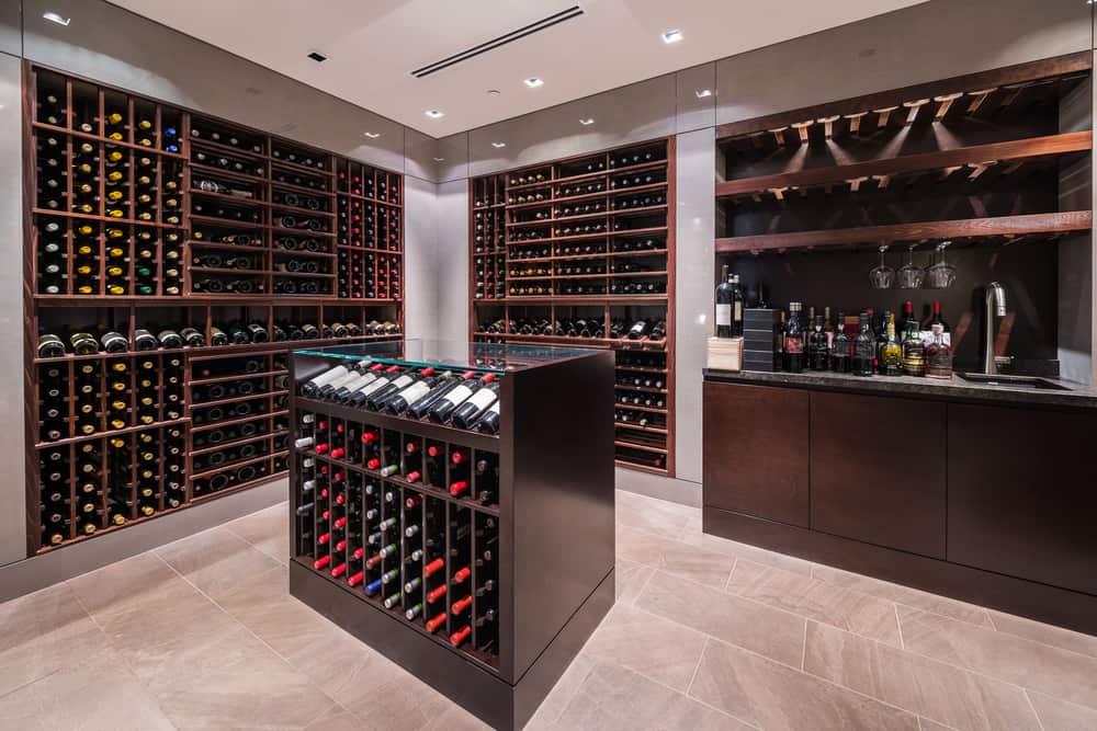 Luxurious wine cellar with wooden racks holding various wine bottles and a small bar area with glasses and liquor bottles