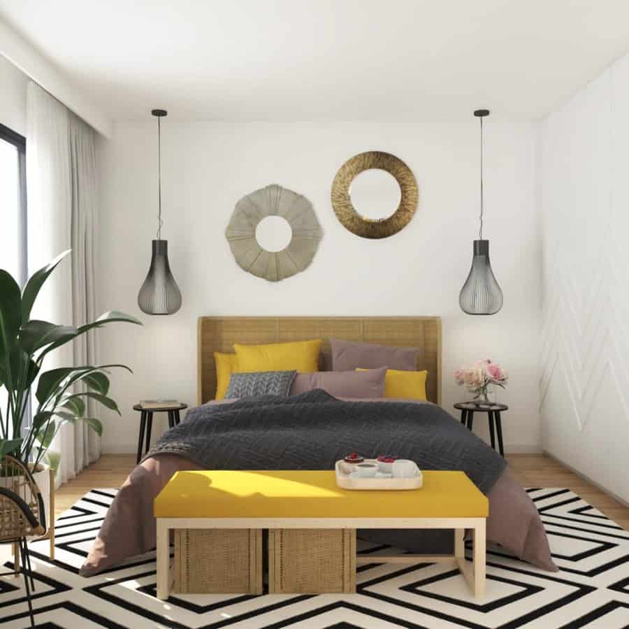 Modern bedroom with a stylish bed, yellow bench, plants, pendant lights, geometric rug, and wall decor in a cozy setting