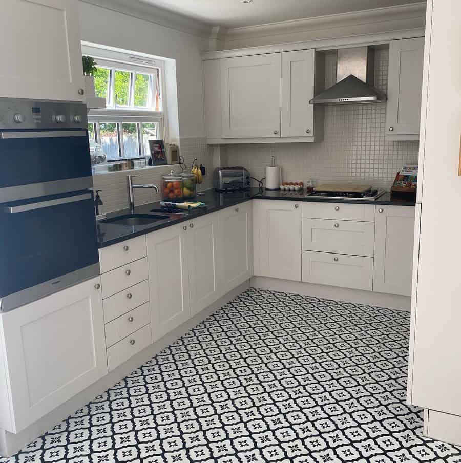 Cozy kitchen with white cabinetry and black and white floor tiles