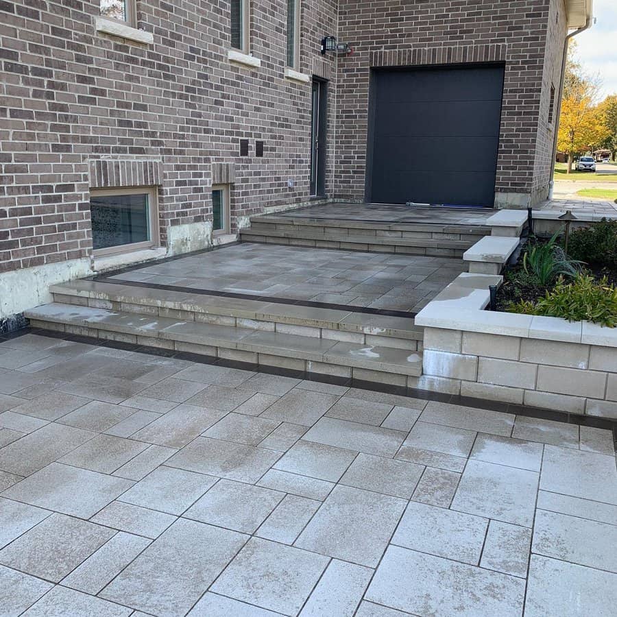 Multi stone patio with steps by brick house