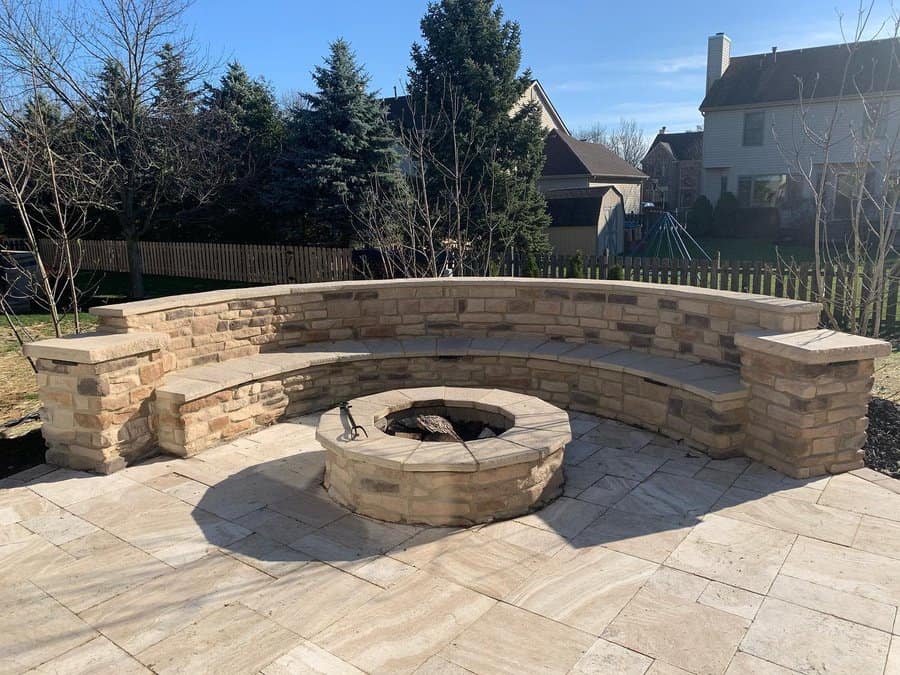 Stone patio with circular fire pit and curved bench