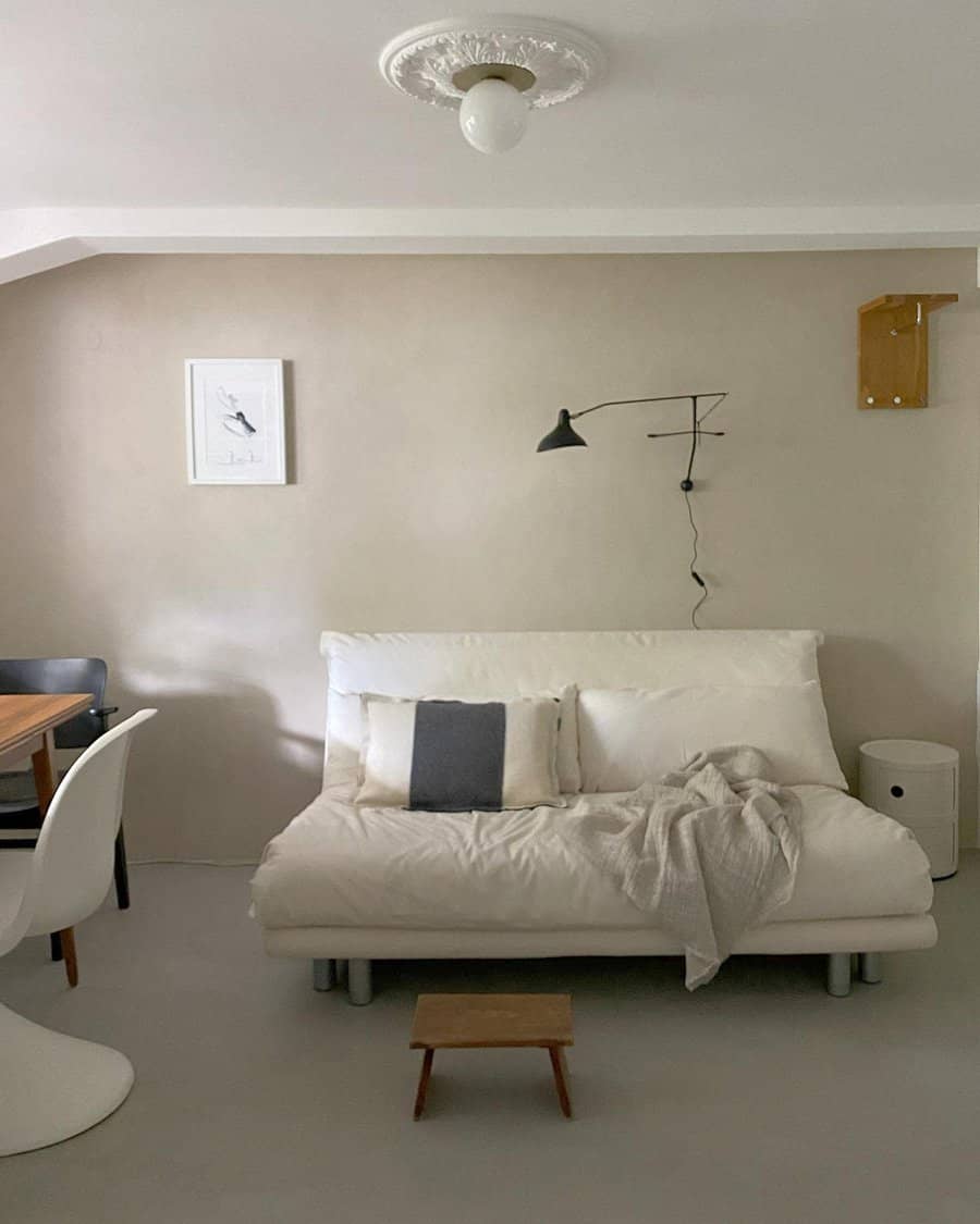 Minimalist white daybed with soft cushions, a cozy throw, and sleek decor, creating a functional and stylish multipurpose living space