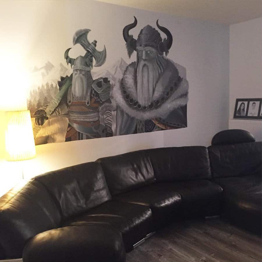 A living room with a black leather sectional sofa and a large fantasy mural on the wall