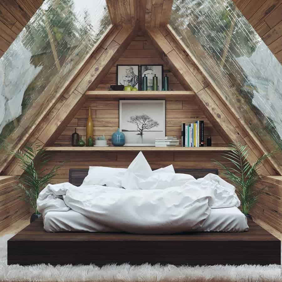 A cozy attic bedroom with a sloped wooden ceiling, skylights, a bed with white bedding, bookshelves, and decorative plants