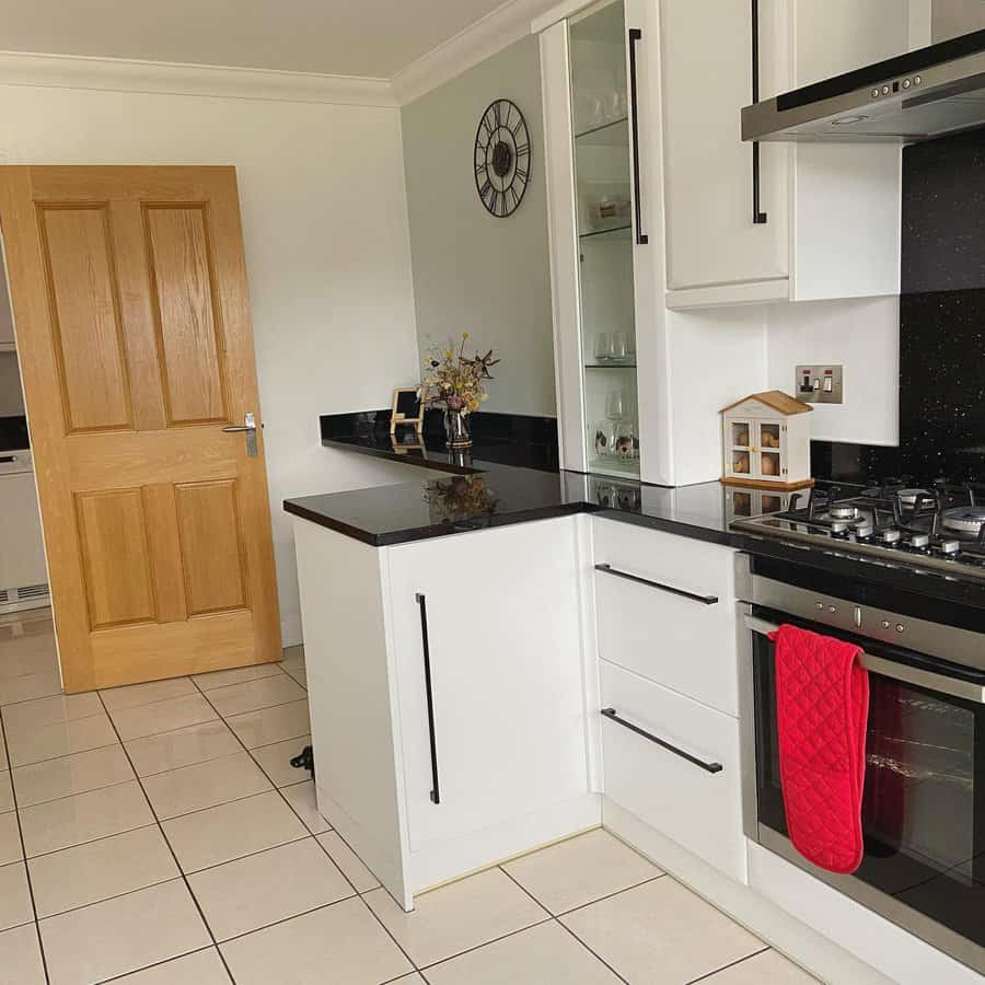 Compact kitchen with white cabinets and tile flooring