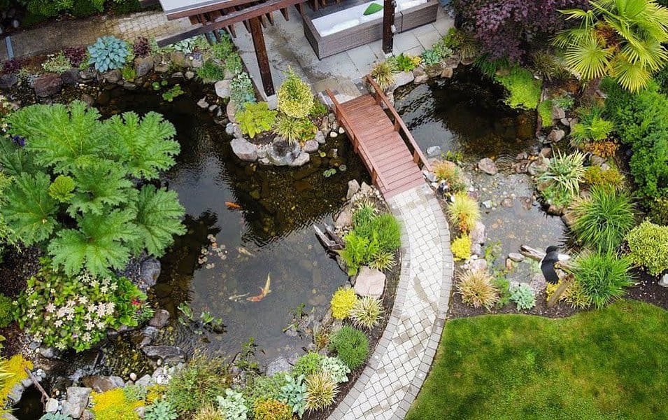 Aerial view of a landscaped garden with pond and footbridge