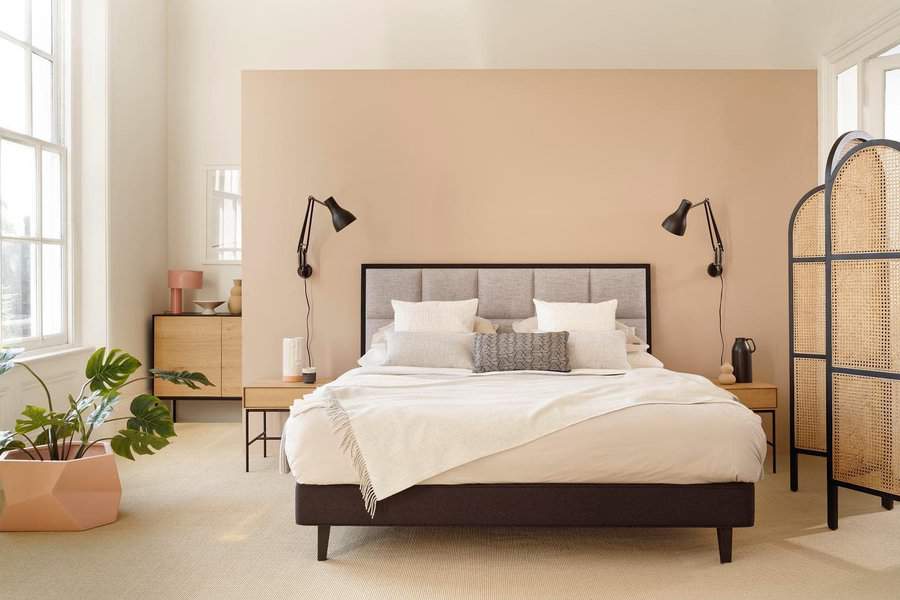 Minimalist bedroom with a bed, beige walls, black side lamps, a room divider, and a potted plant by the large window