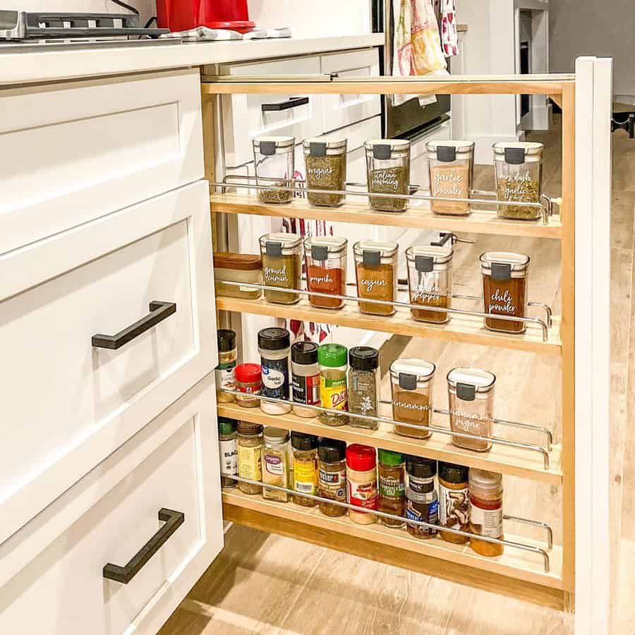 Pull-out spice rack in a white kitchen, neatly organizing labeled spice jars for easy access and efficient storage