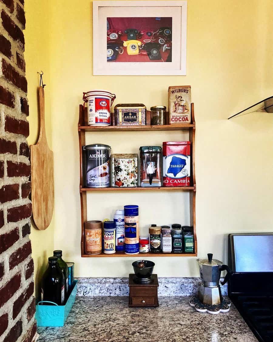 Cozy kitchen corner with a vintage wooden spice rack, decorative tins, a stovetop espresso maker, and a rustic brick wall accent