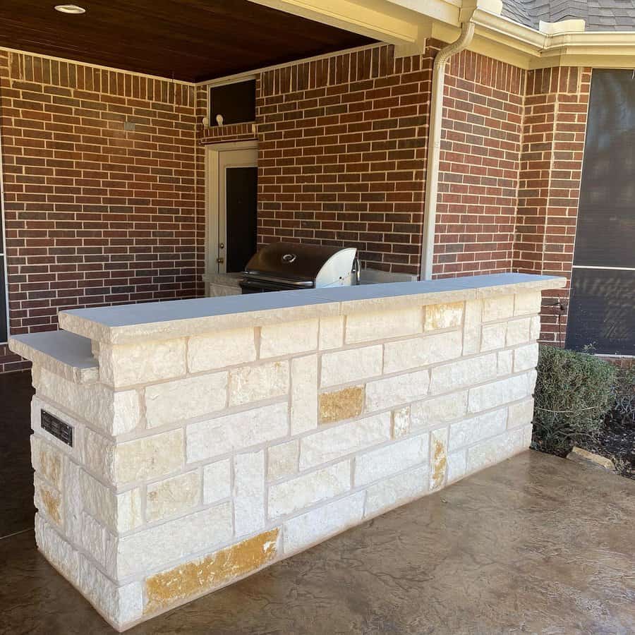 Outdoor kitchen bar with stone facade and built-in grill