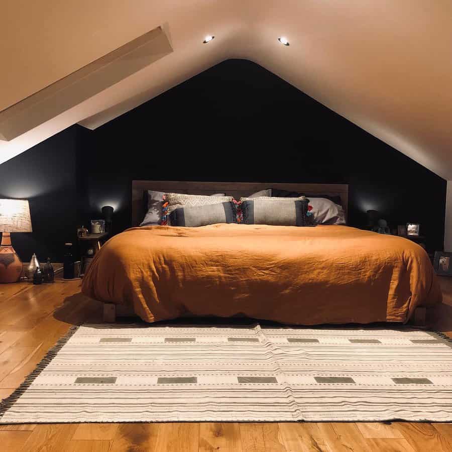 Cozy attic bedroom with a bold black accent wall, warm lighting, and earthy tones. A low wooden bed and rustic decor create a stylish retreat.