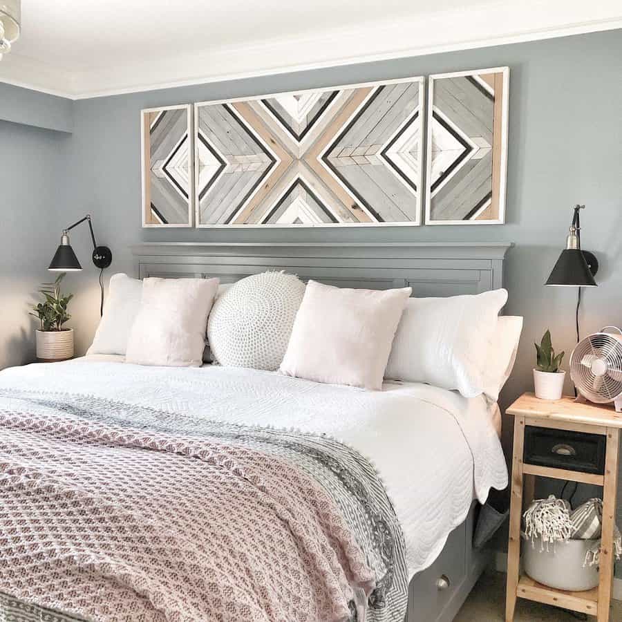 Cozy bedroom with a large bed, geometric artwork above, soft pastel bedding, and small plants on bedside tables