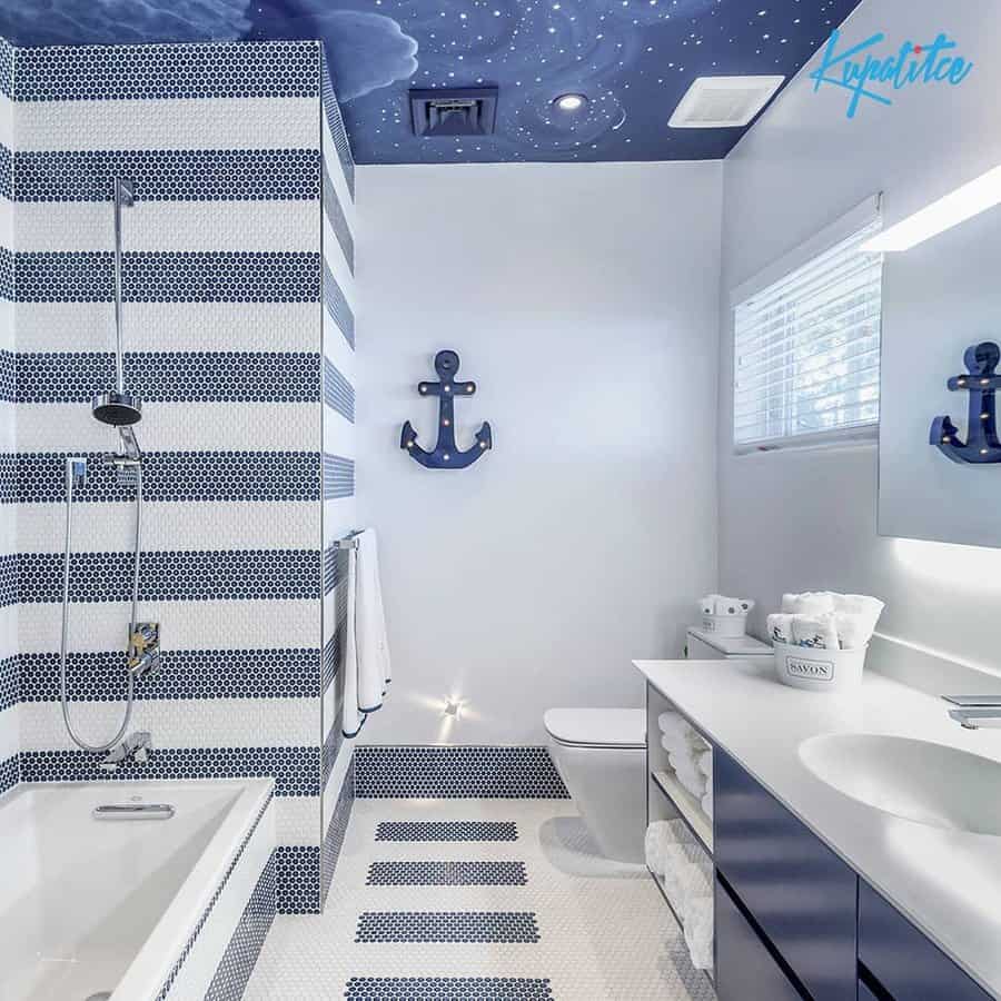 Nautical-themed bathroom with a starry sky ceiling, navy and white striped tiles, and anchor decor, creating a playful and coastal-inspired space.