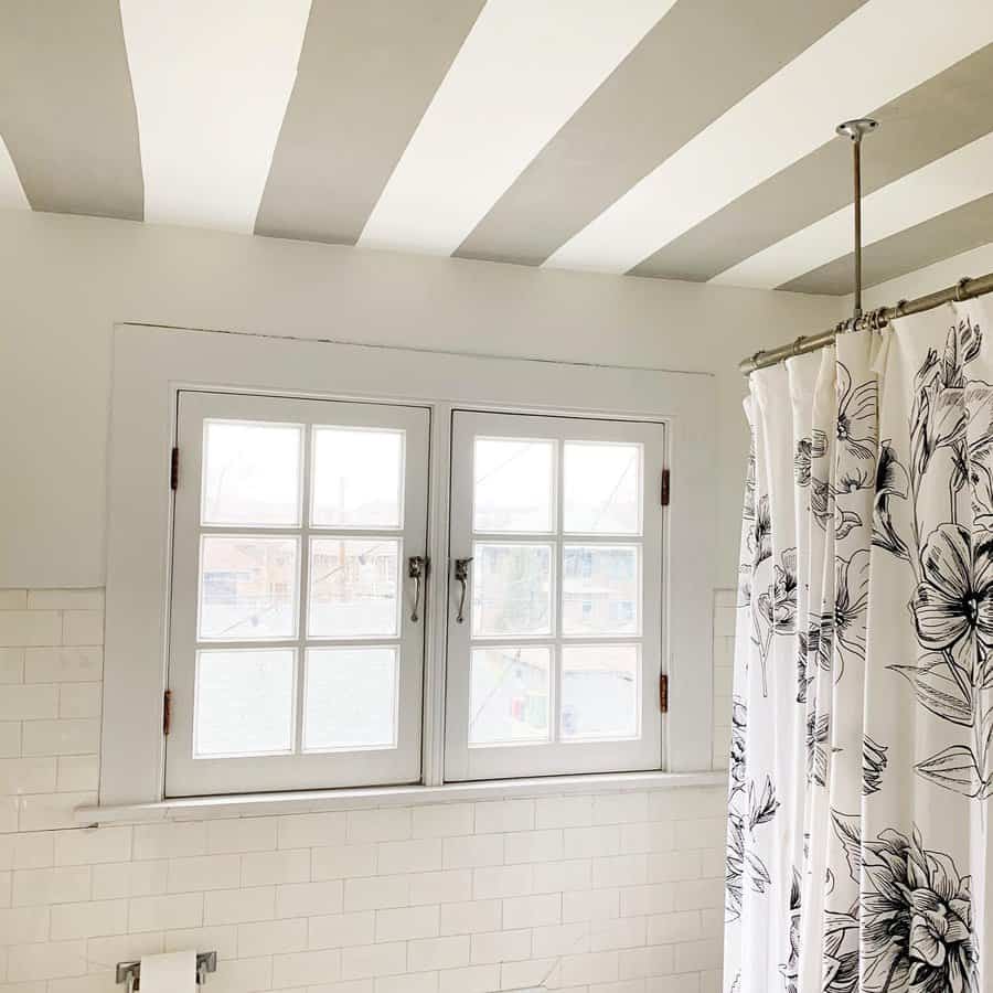 Bright bathroom with a bold striped ceiling in white and gray, adding a playful and modern touch to the classic white subway tile walls.