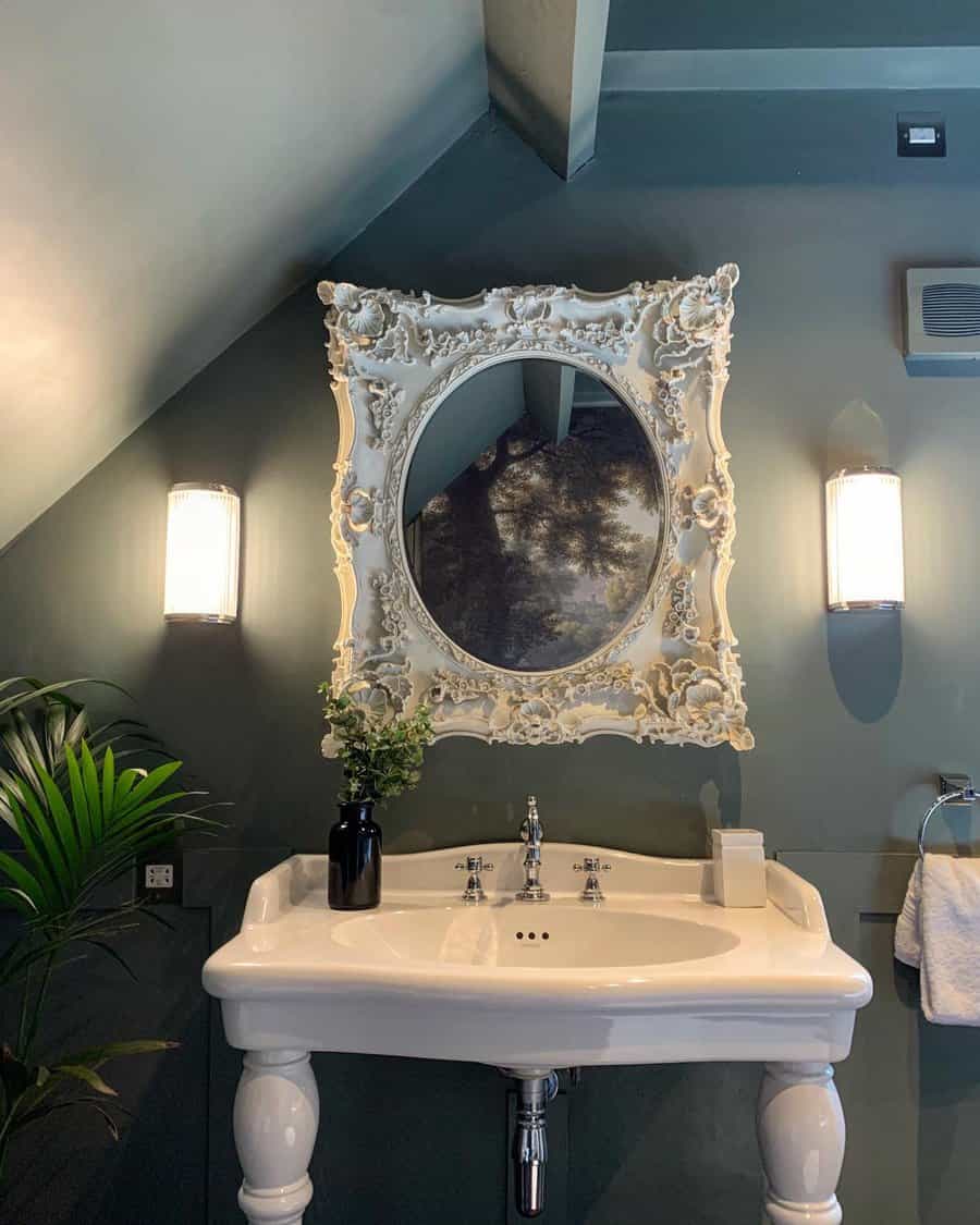 Elegant bathroom with a dark painted ceiling, vintage white pedestal sink, ornate mirror, and moody lighting, creating a dramatic and sophisticated look.