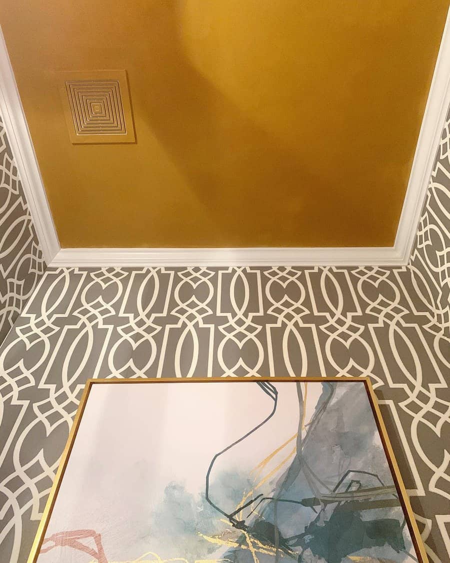 Elegant bathroom with a bold gold ceiling, intricate geometric wallpaper, and abstract artwork, creating a luxurious and stylish atmosphere.