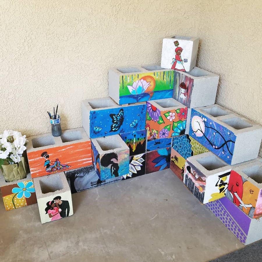 Vibrant DIY cinder block display with hand-painted artistic designs, featuring floral, abstract, and portrait themes, creating a unique and colorful decor piece