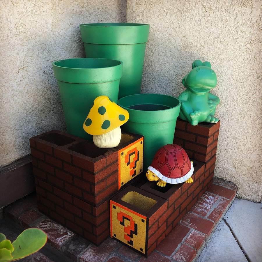 Super Mario-themed DIY cinder block planter, painted like brick blocks with question mark cubes, decorated with green pots and gaming-inspired figurines