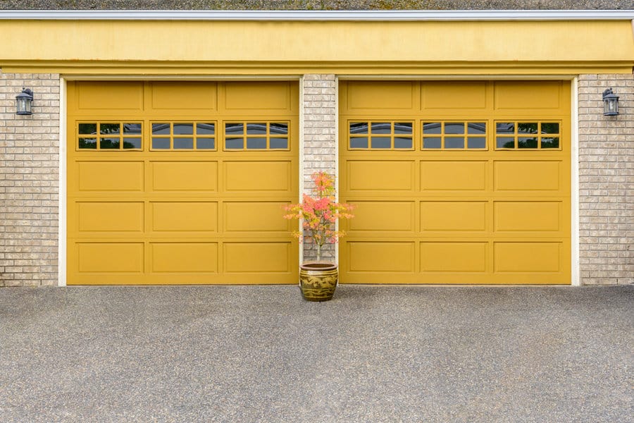 Brick house with double yellow garage doors and a potted plant