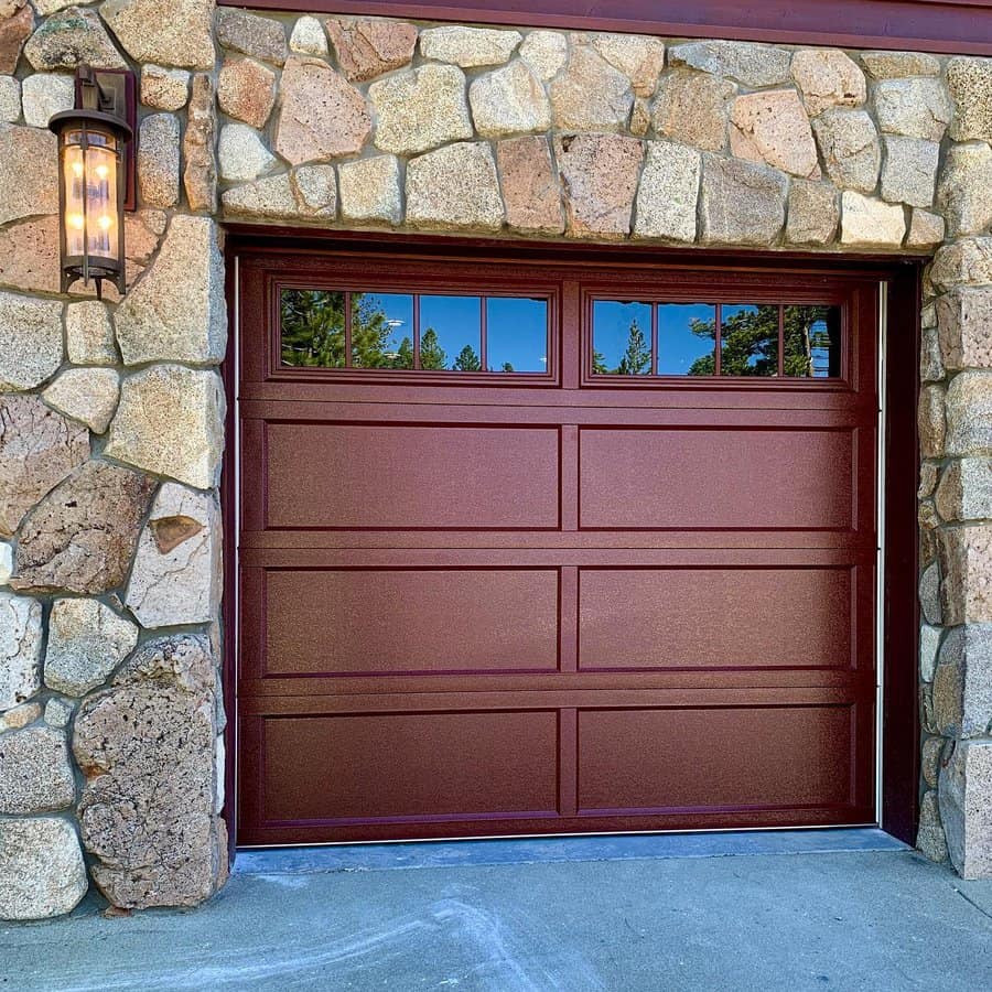 Stone house with a brown garage door and glass panels