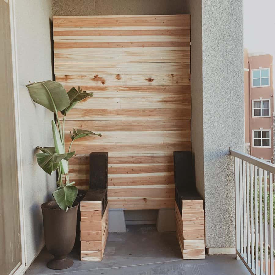 Minimalist DIY balcony seating with cinder blocks and wooden planks, paired with a wood-paneled accent wall and a potted plant for a modern, cozy look