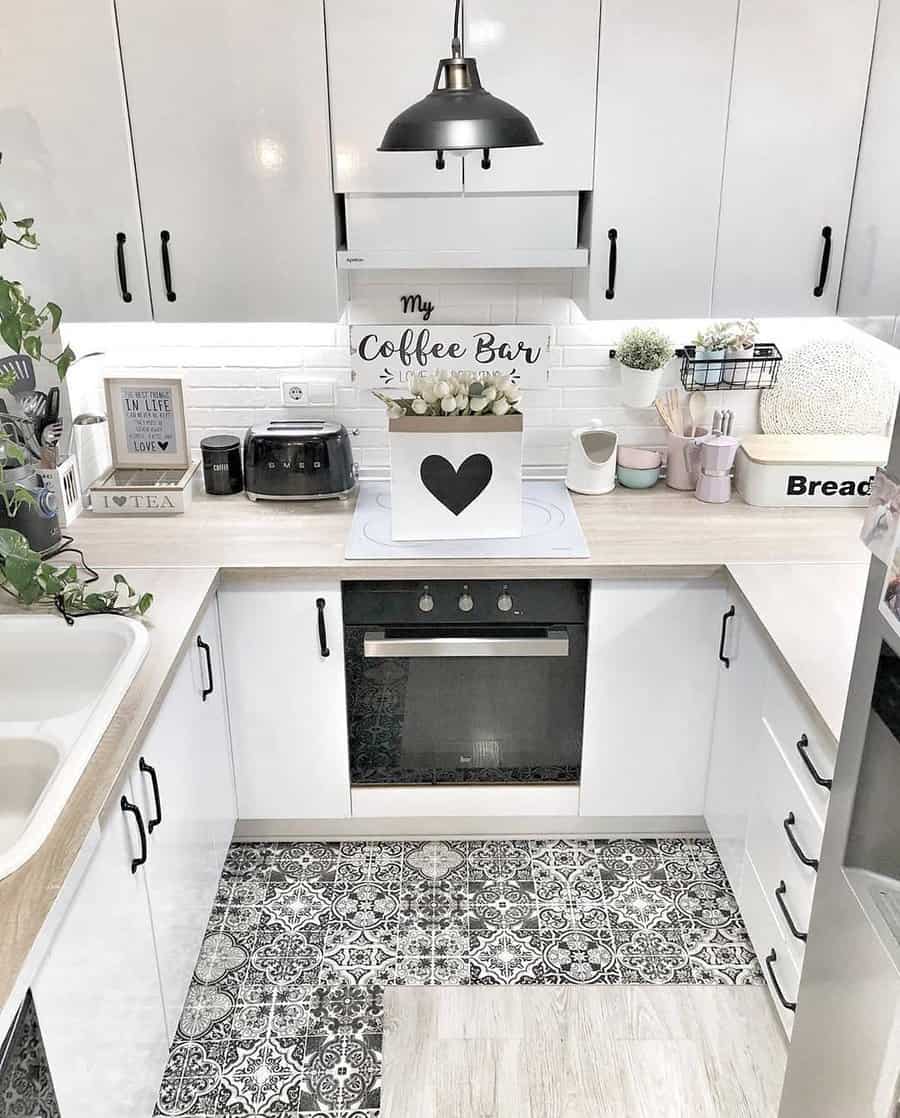 Modern kitchen with white cabinets, patterned floor tiles, black appliances, and a "My Coffee Bar" sign on the countertop